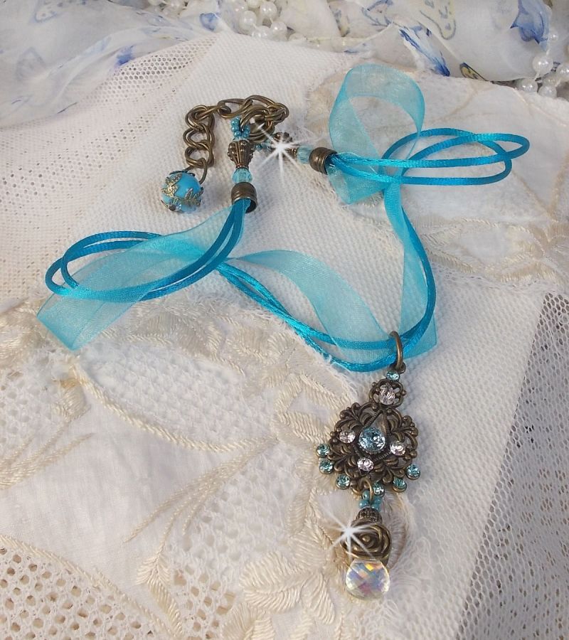 Pendentif Lady in Blue mont&eacute; avec des chandeliers, des cristaux : cabochons, perles rondes et toupies, perles en c&eacute;ramique, cabochons Zirconium, rocailles et rubans. Tout est de couleur Bleu et Bronze