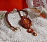 Pendentif artisanal brodé de perles orange et dorées.