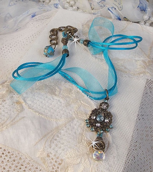 Pendentif Lady in Blue mont&eacute; avec des chandeliers, des cristaux : cabochons, perles rondes et toupies, perles en c&eacute;ramique, cabochons Zirconium, rocailles et rubans. Tout est de couleur Bleu et Bronze