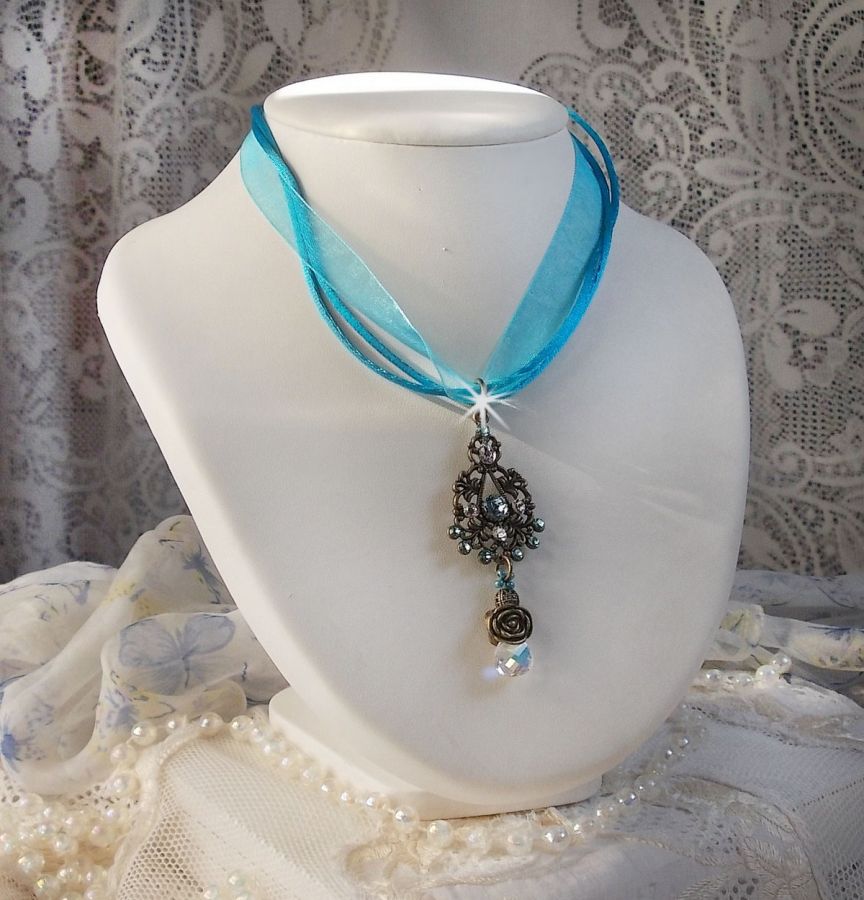 Pendentif Lady in Blue mont&eacute; avec des chandeliers, des cristaux : cabochons, perles rondes et toupies, perles en c&eacute;ramique, cabochons Zirconium, rocailles et rubans. Tout est de couleur Bleu et Bronze