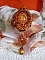 Pendentif artisanal brodé de perles orange et dorées.
