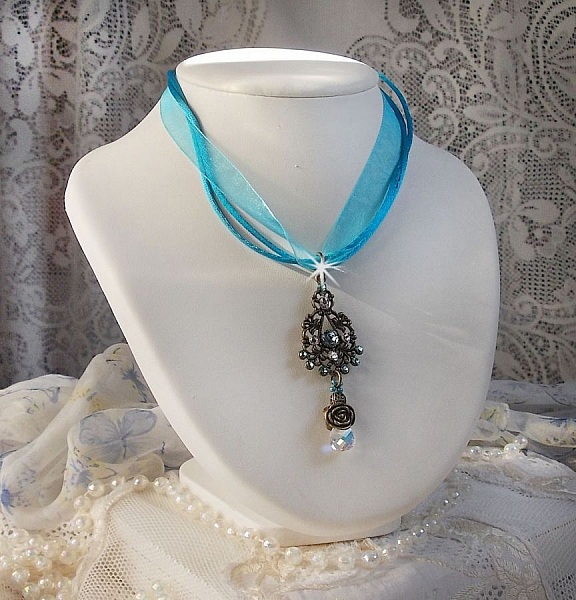 Pendentif Lady in Blue mont&eacute; avec des chandeliers, des cristaux : cabochons, perles rondes et toupies, perles en c&eacute;ramique, cabochons Zirconium, rocailles et rubans. Tout est de couleur Bleu et Bronze