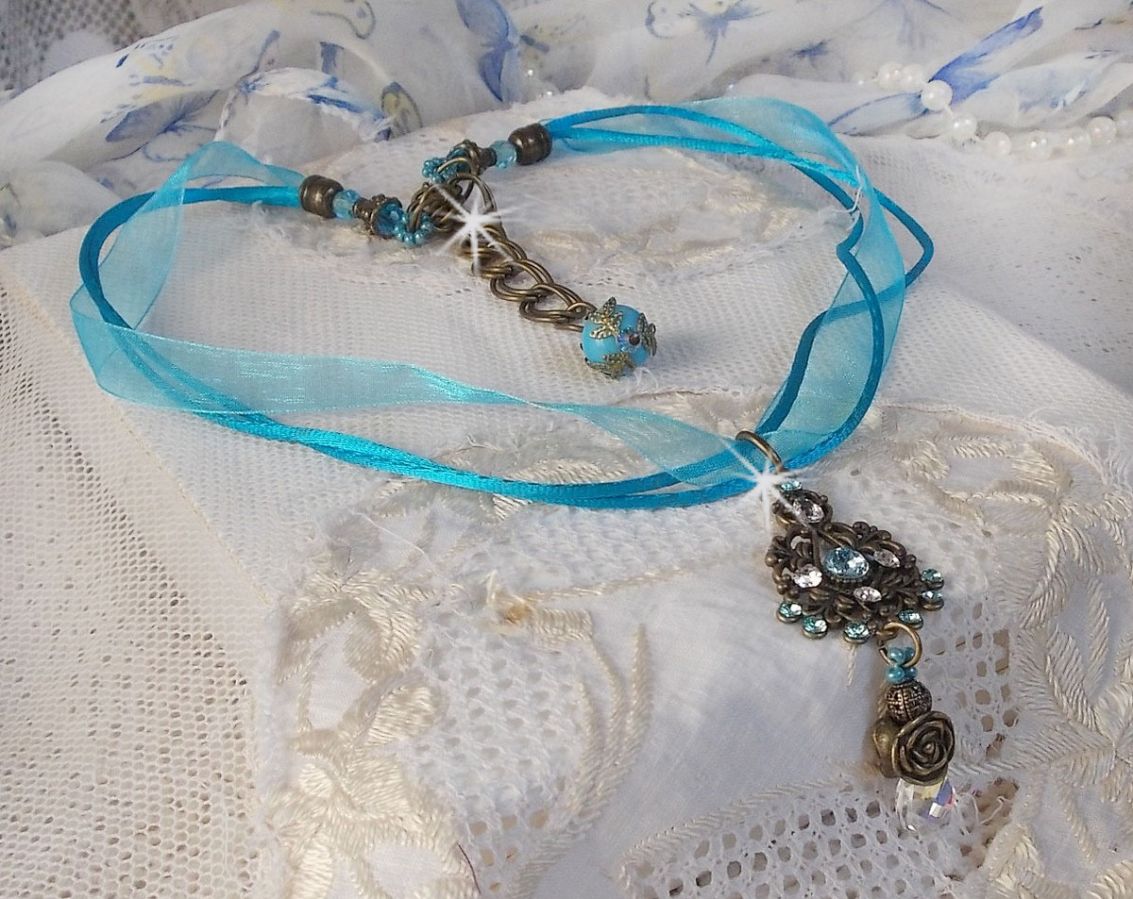 Pendentif Lady in Blue mont&eacute; avec des chandeliers, des cristaux : cabochons, perles rondes et toupies, perles en c&eacute;ramique, cabochons Zirconium, rocailles et rubans. Tout est de couleur Bleu et Bronze
