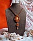 Pendentif artisanal brodé aux perles orange et tons dorés.