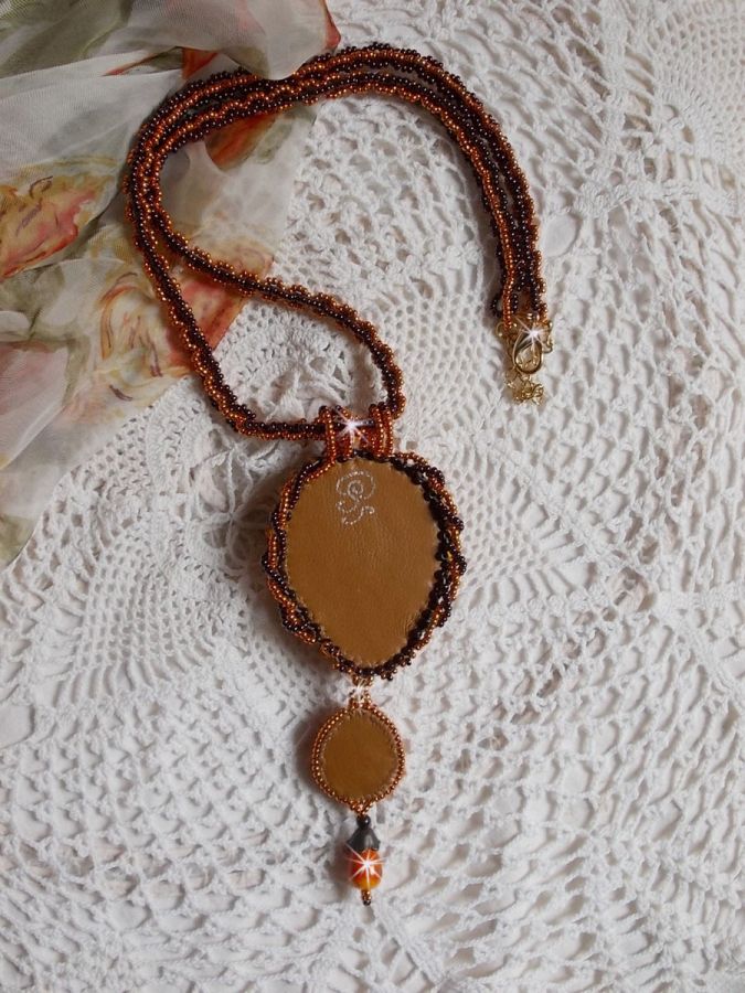 Pendentif artisanal brodé aux perles orange et marron.