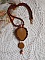 Pendentif artisanal brodé aux perles orange et marron.