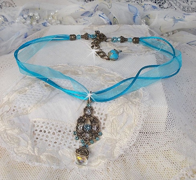Pendentif Lady in Blue mont&eacute; avec des chandeliers, des cristaux : cabochons, perles rondes et toupies, perles en c&eacute;ramique, cabochons Zirconium, rocailles et rubans. Tout est de couleur Bleu et Bronze