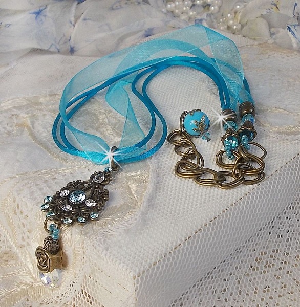 Pendentif Lady in Blue mont&eacute; avec des chandeliers, des cristaux : cabochons, perles rondes et toupies, perles en c&eacute;ramique, cabochons Zirconium, rocailles et rubans. Tout est de couleur Bleu et Bronze