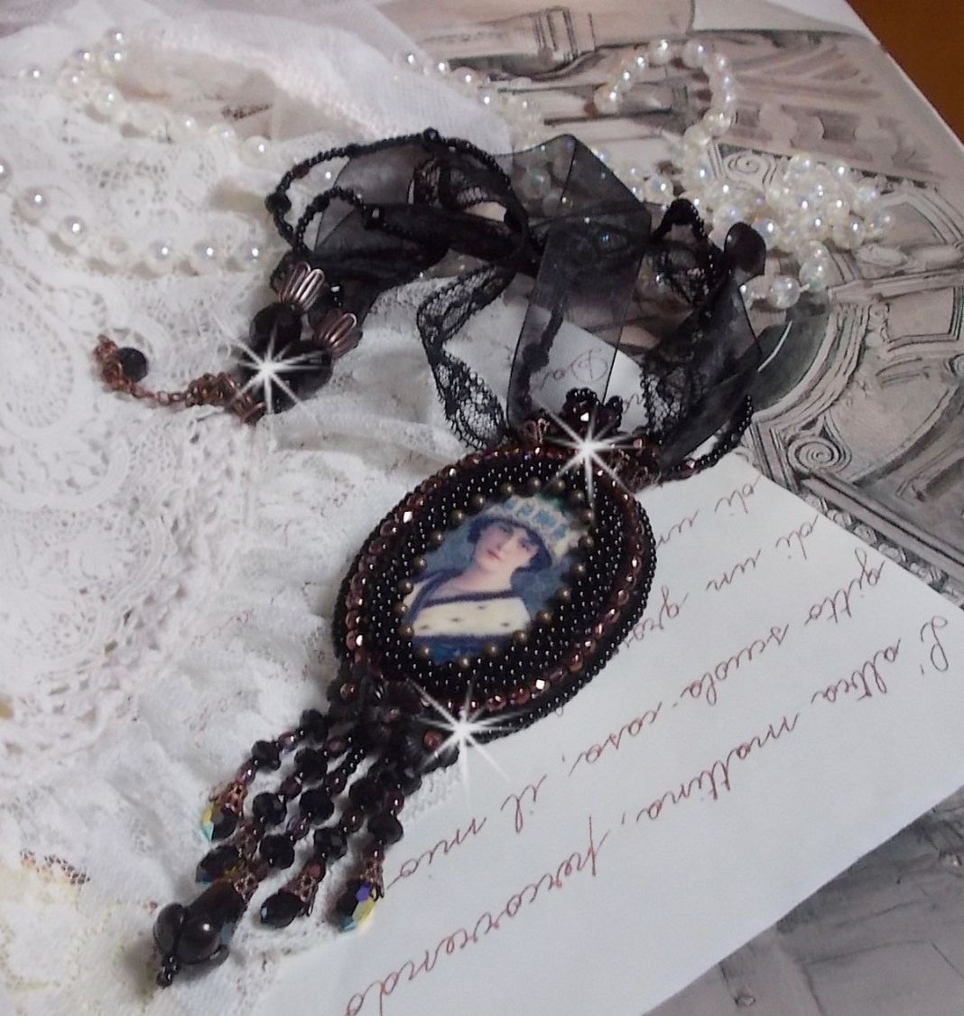 Pendentif Midnight Daisy avec un cabochon en bois repr&eacute;sentant une femme en chapeau Bleu, brod&eacute; avec des fleurs lucites, coupelles et facettes. Le tout est fini avec une dentelle Noire et un ruban