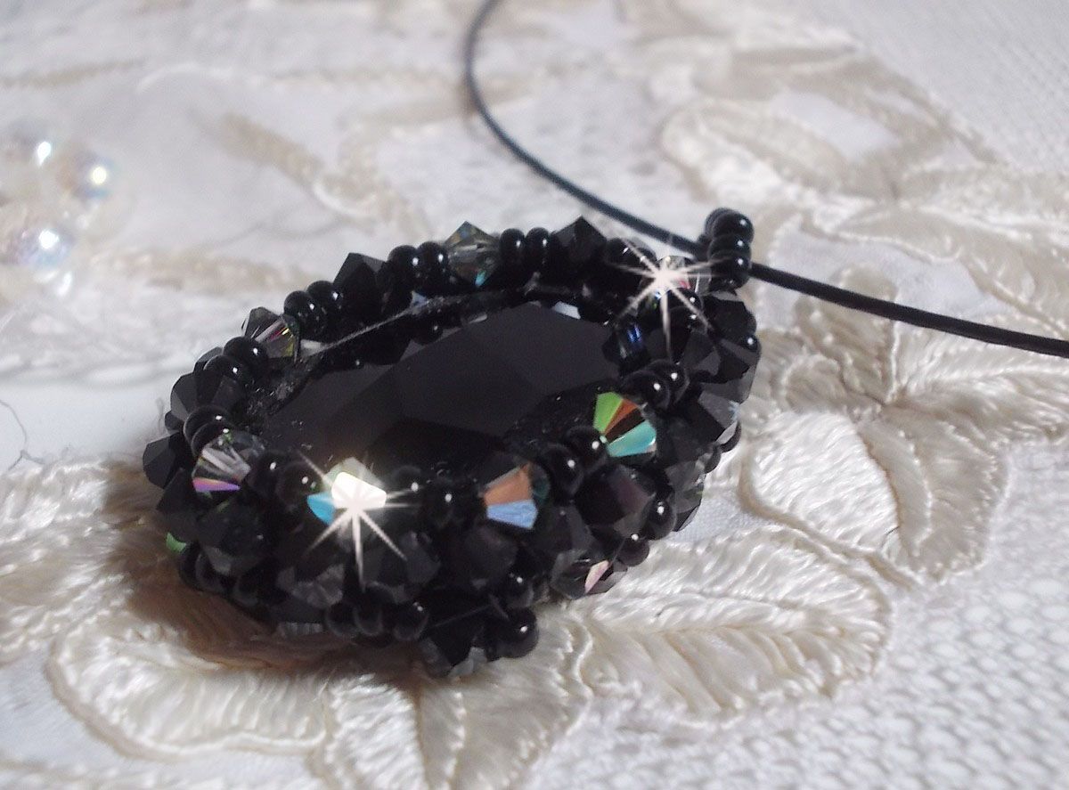 Pendentif Mirano incarne parfaitement l&rsquo;&eacute;l&eacute;gance avec un cabochon ovale facett&eacute; en Cristal cercl&eacute; de rocailles et toupies aux couleurs Noires et Argent&eacute;es. Mont&eacute; sur un tour du cou c&acirc;bl&eacute; et cir&eacute; Noir 