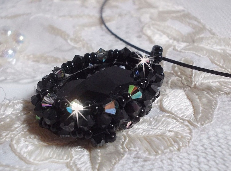 Pendentif Mirano incarne parfaitement l&rsquo;&eacute;l&eacute;gance avec un cabochon ovale facett&eacute; en Cristal cercl&eacute; de rocailles et toupies aux couleurs Noires et Argent&eacute;es. Mont&eacute; sur un tour du cou c&acirc;bl&eacute; et cir&eacute; Noir 
