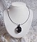 Pendentif Mirano incarne parfaitement l&rsquo;&eacute;l&eacute;gance avec un cabochon ovale facett&eacute; en Cristal cercl&eacute; de rocailles et toupies aux couleurs Noires et Argent&eacute;es. Mont&eacute; sur un tour du cou c&acirc;bl&eacute; et cir&eacute; Noir 