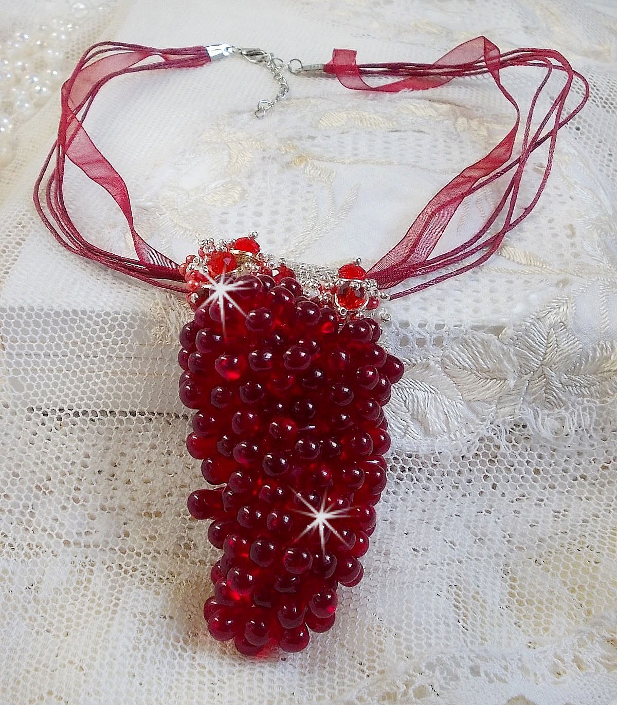 Pendentif Tendre Rouge mont&eacute; avec des gouttes en verre rouge, des perles rondes facett&eacute;es et des perles nacr&eacute;es