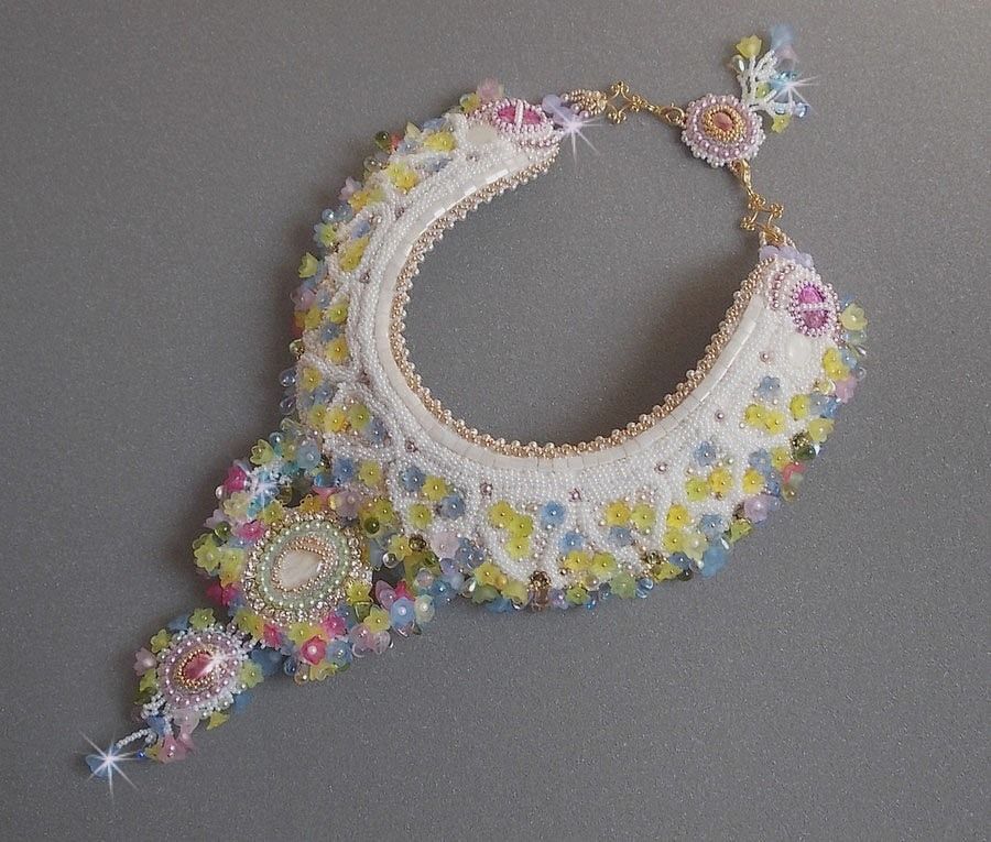 Plastron Envol&eacute;e Fleurie Haute Couture brod&eacute; avec des cabochons Nacre et R&eacute;sine aux couleurs Fuchsia et Ivoire, s&rsquo;ajoute des fleurs lucites, feuilles en verre, chatons et perles en Cristal.