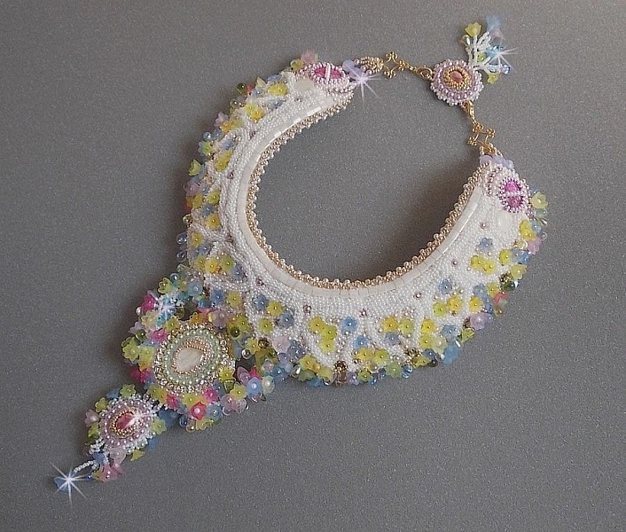 Plastron Envol&eacute;e Fleurie Haute Couture brod&eacute; avec des cabochons Nacre et R&eacute;sine aux couleurs Fuchsia et Ivoire, s&rsquo;ajoute des fleurs lucites, feuilles en verre, chatons et perles en Cristal.