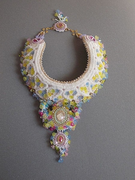 Plastron Envol&eacute;e Fleurie Haute Couture brod&eacute; avec des cabochons Nacre et R&eacute;sine aux couleurs Fuchsia et Ivoire, s&rsquo;ajoute des fleurs lucites, feuilles en verre, chatons et perles en Cristal.