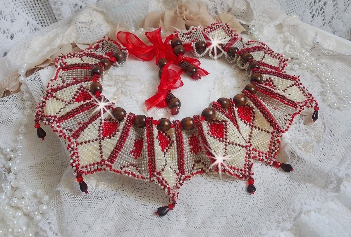 Collier Romane plastron mont&eacute; avec une abondance de rocailles aux couleurs : Bordeaux, Ivoire et Rouge &agrave; laquelle s'ajoute des gouttes plates, perles en bois, perles en laiton pour un style Ethnique