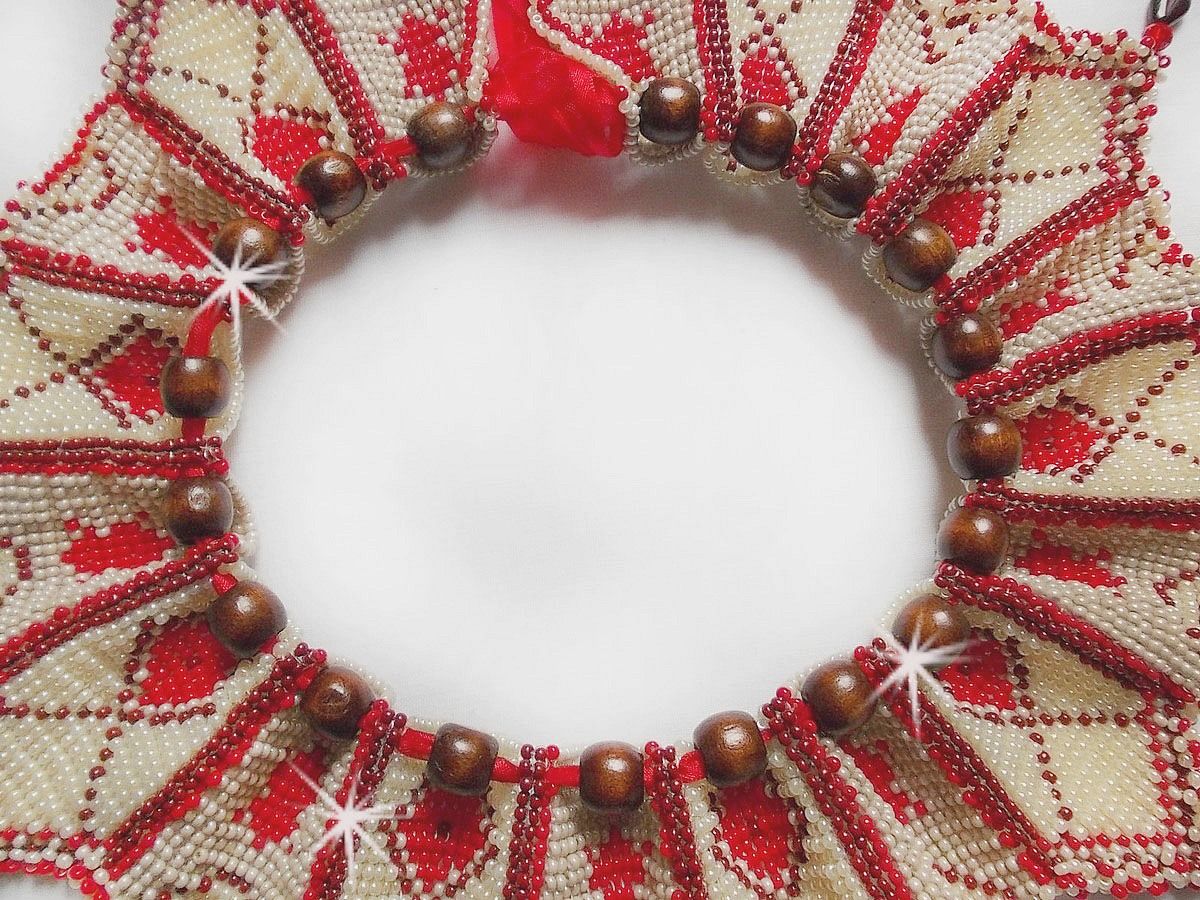 Collier Romane plastron mont&eacute; avec une abondance de rocailles aux couleurs : Bordeaux, Ivoire et Rouge &agrave; laquelle s'ajoute des gouttes plates, perles en bois, perles en laiton pour un style Ethnique