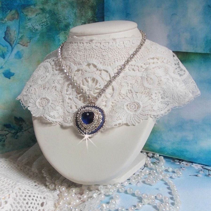 Collier Saphir Bleu brod&eacute; &agrave; l'aiguille avec un c&oelig;ur en cristal de Swarovski, rocailles argent&eacute;es Miyuki, strass, un fermoir et une cha&icirc;nette d'extension en argent 925/1000. Un voyage si lointain.