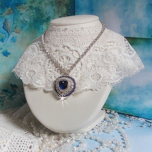 Collier Saphir Bleu brod&eacute; &agrave; l'aiguille avec un c&oelig;ur en cristal de Swarovski, rocailles argent&eacute;es Miyuki, strass, un fermoir et une cha&icirc;nette d'extension en argent 925/1000. Un voyage si lointain.
