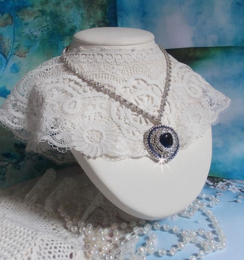 Collier Saphir Bleu brod&eacute; &agrave; l'aiguille avec un c&oelig;ur en cristal de Swarovski, rocailles argent&eacute;es Miyuki, strass, un fermoir et une cha&icirc;nette d'extension en argent 925/1000. Un voyage si lointain.