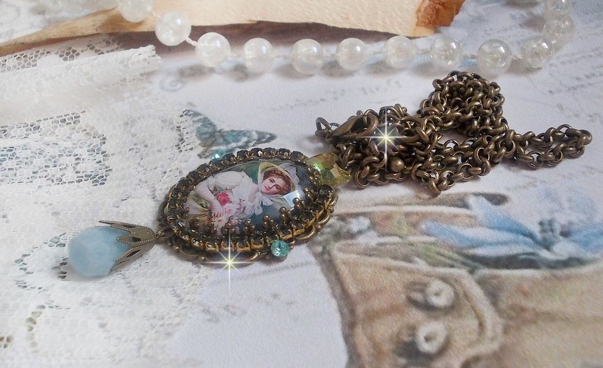 Pendentif Douce Dame cr&eacute;&eacute; avec un cabochon repr&eacute;sentant une femme au chapeau blanc orn&eacute; de cristaux, des accessoires de couleur Bronze et un jade teint&eacute; bleu 
