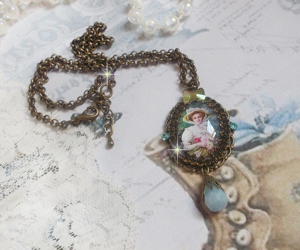 Pendentif Douce Dame cr&eacute;&eacute; avec un cabochon repr&eacute;sentant une femme au chapeau blanc orn&eacute; de cristaux, des accessoires de couleur Bronze et un jade teint&eacute; bleu 
