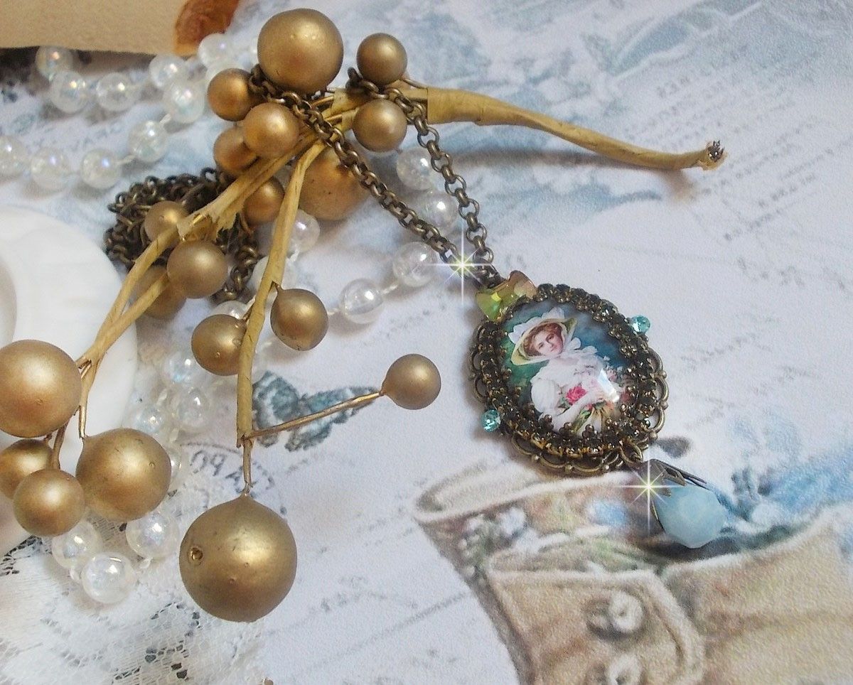 Pendentif Douce Dame cr&eacute;&eacute; avec un cabochon repr&eacute;sentant une femme au chapeau blanc orn&eacute; de cristaux, des accessoires de couleur Bronze et un jade teint&eacute; bleu 