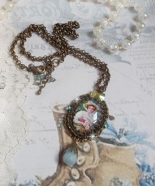 Pendentif Douce Dame cr&eacute;&eacute; avec un cabochon repr&eacute;sentant une femme au chapeau blanc orn&eacute; de cristaux, des accessoires de couleur Bronze et un jade teint&eacute; bleu 
