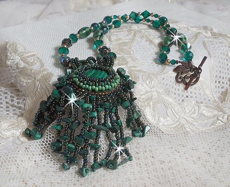 Pendentif Emerald avec un cabochon ovale en Malachite orn&eacute; de chips avec cristaux : perles rondes et toupies Emerald. S&rsquo;ajoute des perles en forme d&rsquo;olives. Brod&eacute;s sur fermoir en T. Un style Ethnique