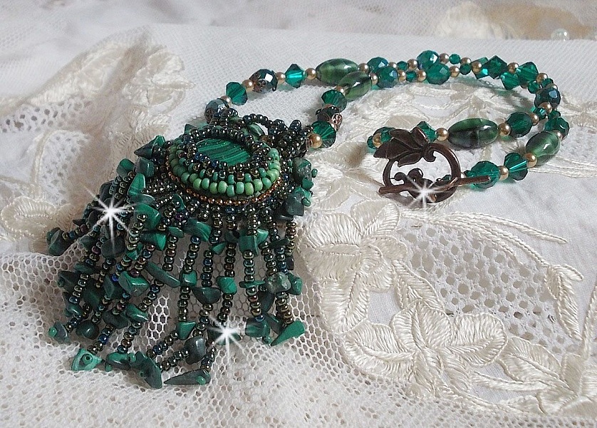 Pendentif Emerald avec un cabochon ovale en Malachite orn&eacute; de chips avec cristaux : perles rondes et toupies Emerald. S&rsquo;ajoute des perles en forme d&rsquo;olives. Brod&eacute;s sur fermoir en T. Un style Ethnique
