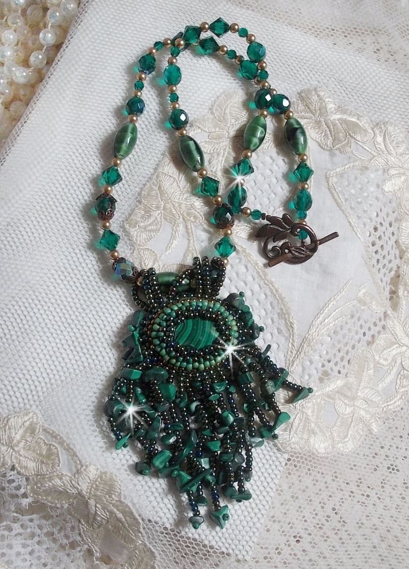 Pendentif Emerald avec un cabochon ovale en Malachite orn&eacute; de chips avec cristaux : perles rondes et toupies Emerald. S&rsquo;ajoute des perles en forme d&rsquo;olives. Brod&eacute;s sur fermoir en T. Un style Ethnique