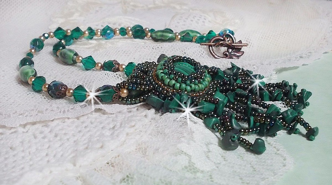Pendentif Emerald avec un cabochon ovale en Malachite orn&eacute; de chips avec cristaux : perles rondes et toupies Emerald. S&rsquo;ajoute des perles en forme d&rsquo;olives. Brod&eacute;s sur fermoir en T. Un style Ethnique