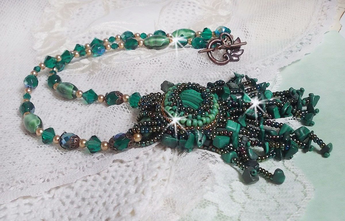 Pendentif Emerald avec un cabochon ovale en Malachite orn&eacute; de chips avec cristaux : perles rondes et toupies Emerald. S&rsquo;ajoute des perles en forme d&rsquo;olives. Brod&eacute;s sur fermoir en T. Un style Ethnique