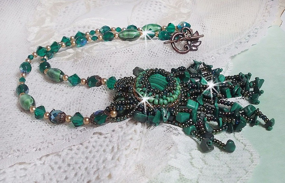 Pendentif Emerald avec un cabochon ovale en Malachite orn&eacute; de chips avec cristaux : perles rondes et toupies Emerald. S&rsquo;ajoute des perles en forme d&rsquo;olives. Brod&eacute;s sur fermoir en T. Un style Ethnique