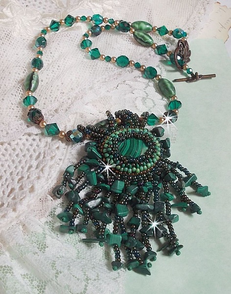 Pendentif Emerald avec un cabochon ovale en Malachite orn&eacute; de chips avec cristaux : perles rondes et toupies Emerald. S&rsquo;ajoute des perles en forme d&rsquo;olives. Brod&eacute;s sur fermoir en T. Un style Ethnique