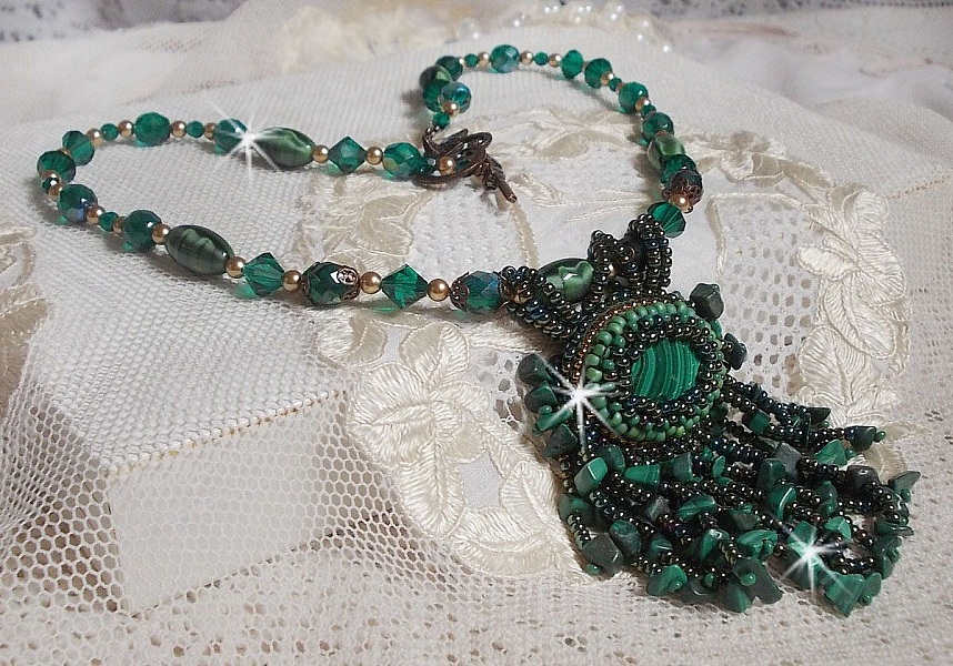 Pendentif Emerald avec un cabochon ovale en Malachite orn&eacute; de chips avec cristaux : perles rondes et toupies Emerald. S&rsquo;ajoute des perles en forme d&rsquo;olives. Brod&eacute;s sur fermoir en T. Un style Ethnique