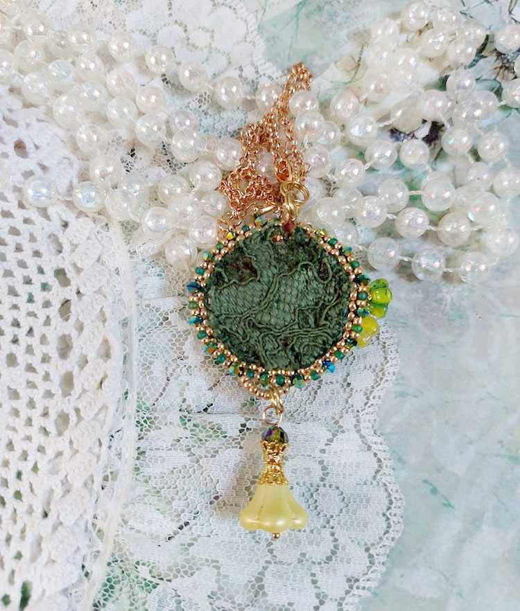 Pendentif artisanal brodé vert avec perles et dentelle blanche.