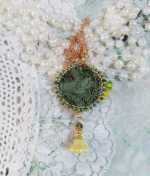 Pendentif artisanal brodé vert avec perles et dentelle blanche.