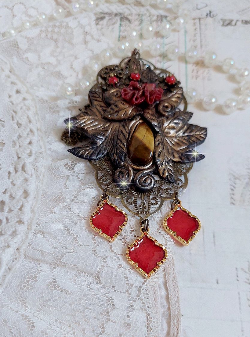 Pendentif M&eacute;lodie avec un cabochon &OElig;il de tigre orn&eacute; de perles en Jade Rouge vein&eacute; de Noir sur fleurs 5 p&eacute;tales et estampes mont&eacute;s sur une cha&icirc;ne bronze. Les pendants sont en r&eacute;sine &eacute;poxy Rouge