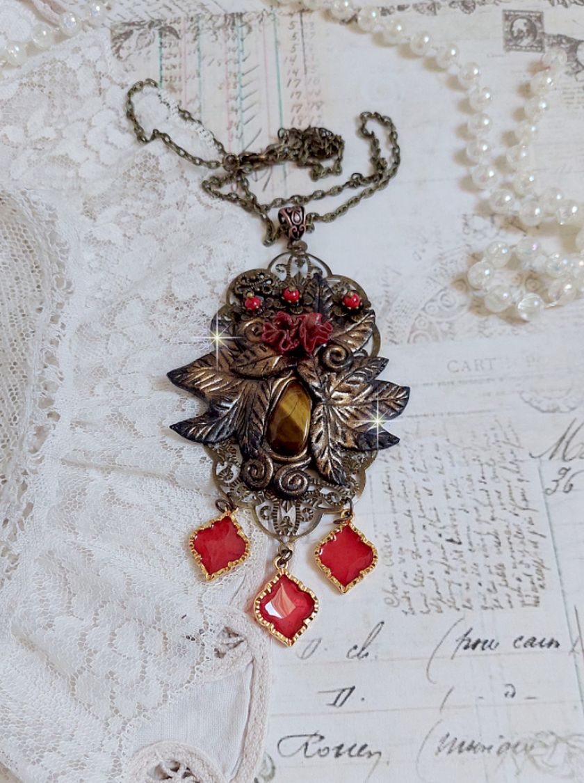 Pendentif M&eacute;lodie avec un cabochon &OElig;il de tigre orn&eacute; de perles en Jade Rouge vein&eacute; de Noir sur fleurs 5 p&eacute;tales et estampes mont&eacute;s sur une cha&icirc;ne bronze. Les pendants sont en r&eacute;sine &eacute;poxy Rouge
