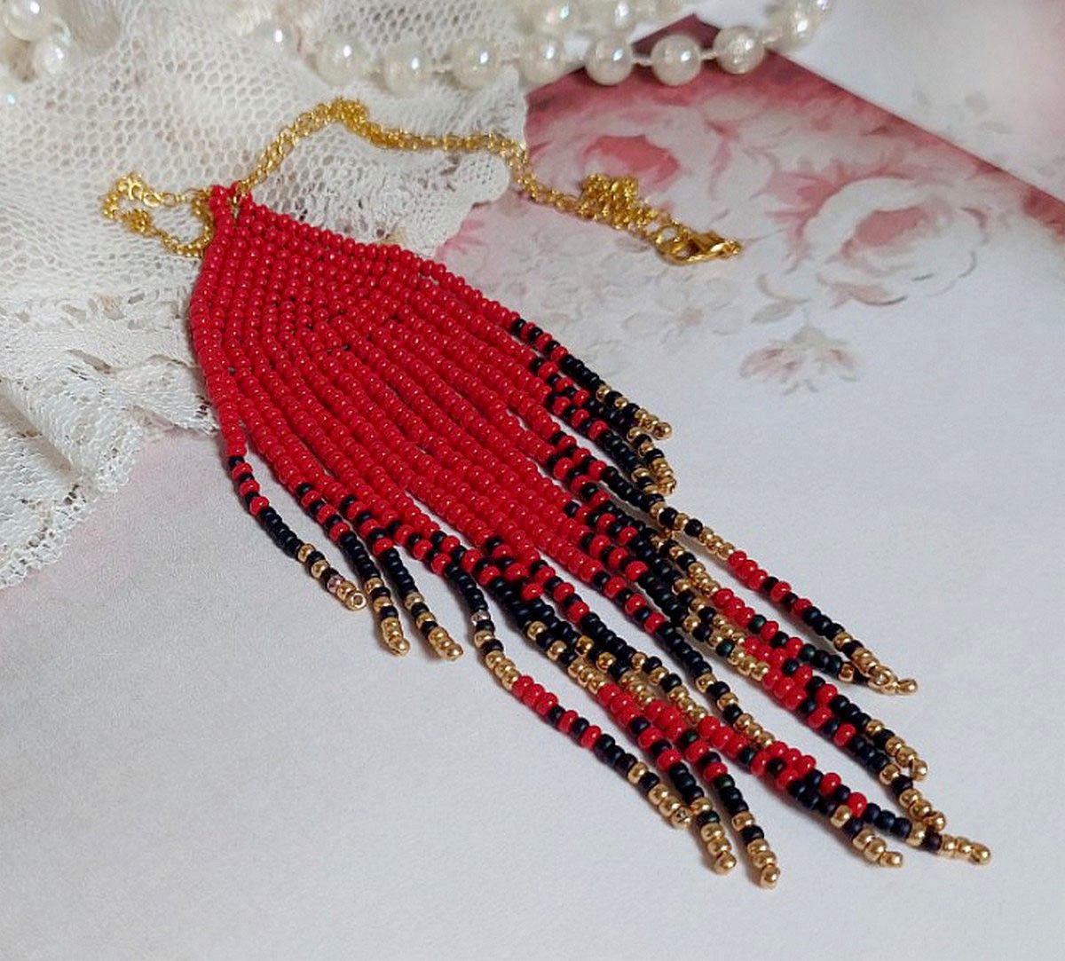Pendentif Tourbillons de Rouge avec des rocailles aux trois couleurs : Rouge, Bleu Iris et Dor&eacute; pour les pampilles. Le tout est mont&eacute; sur une cha&icirc;ne et un mousqueton en Plaqu&eacute; Or