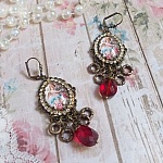 BO Petit Ange avec des cabochons d&rsquo;anges orn&eacute;s d&rsquo;une cha&icirc;ne strass Cristal, breloques, gouttes facett&eacute;es en verre de couleur Siam. Mont&eacute;s sur des pendentifs et des dormeuses en Laiton