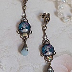 BO Dame au chapeau fleuri repr&eacute;sentant une femme au chapeau entour&eacute; d&rsquo;un ruban noir est mont&eacute; sur des estampes avec des n&oelig;uds en cristal. Une belle &eacute;l&eacute;gance avec ces gouttes en Jade teint&eacute;es de Bleu