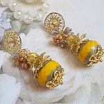 BO Lumi&egrave;re Opale Jaune avec des perles potirons jaunes &agrave; laquelle s&rsquo;ajoute des fleurs, cabochons en cristal, coupelles et perles rondes. Mont&eacute;s sur clous d&rsquo;oreilles en M&eacute;tal. Un style moderne