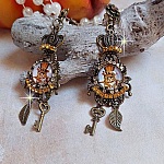 BO Chatibo Steampunk mont&eacute;es avec cabochons ronds en verre repr&eacute;sentant un chat chapeaut&eacute; Haute de Forme Orange. Strass&eacute;es avec une couronne, breloques cl&eacute;s et feuilles. Mont&eacute;es sur clips Bronze
