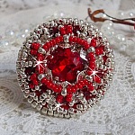 Bague Drigon Red brod&eacute;e avec un cabochon carr&eacute; Rouge sur une estampe Argent&eacute;e. Orn&eacute;e de chatons en Cristal puis model&eacute;e avec des rocailles et perles. Le tout est mont&eacute; sur une bague r&eacute;glable argent&eacute;e 