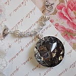 Pendentif Coco brod&eacute; avec des cristaux de Swarovski et un m&eacute;daillon cristal fum&eacute;
