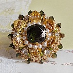 Bague L&rsquo;Oiseau des Iles Vert Dor&eacute;e avec un cabochon Vert sur une estampe dor&eacute;e orn&eacute;e de cristaux : toupies et chatons. Les perles rondes nacr&eacute;es Ivoire et Olivine compl&egrave;te cette bague r&eacute;glable. 