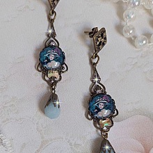 BO Dame au chapeau fleuri repr&eacute;sentant une femme au chapeau entour&eacute; d&rsquo;un ruban noir est mont&eacute; sur des estampes avec des n&oelig;uds en cristal. Une belle &eacute;l&eacute;gance avec ces gouttes en Jade teint&eacute;es de Bleu
